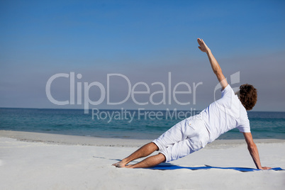 Man performing yoga at beach