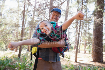 Playful father carrying son in forest