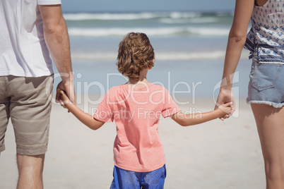 Rear view of boy holding hands with parents