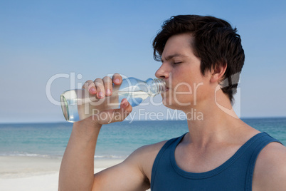 Man drinking water from bottle at beach