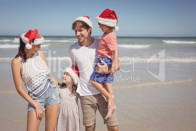 Happy family wearing Santa hat at beach