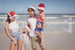 Happy family wearing Santa hat at beach