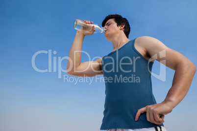 Man drinking water from bottle at beach