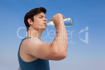 Man drinking water from bottle at beach