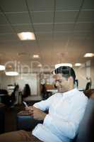 Smiling businessman using mobile phone while sitting at office