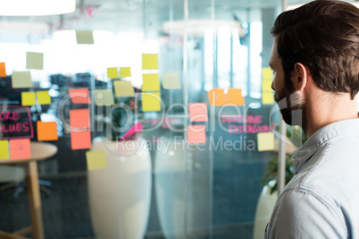 Close up of businessman looking at adhesive notes and strategy on glass