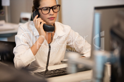 Businesswoman using telephone while sitting at office