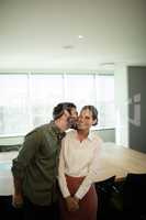 Businessman kissing businesswoman in meeting room