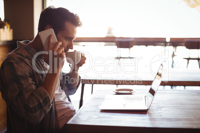 Man talking on mobile phone while having coffee