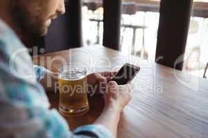 Man using mobile phone while having beer