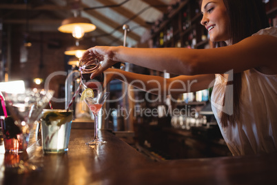 Pretty bartender pouring a cocktail drink in the glass