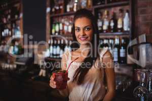 Female bartender holding a cocktail drink at bar counter