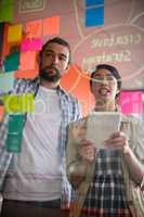 Male and female executives discussing over sticky notes