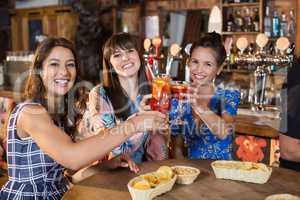 Portrait of smiling female friends toasting drinks