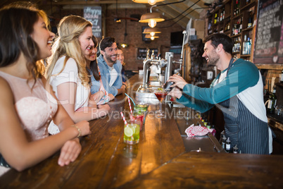 Cheerful bartender interacting with customers while making drink