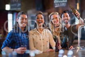 Portrait of happy friends standing by bar counter