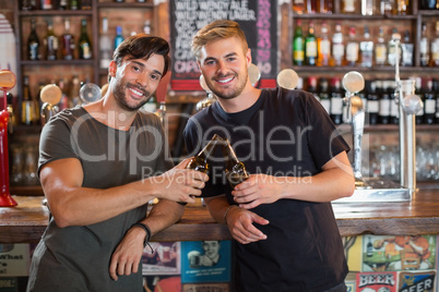 Portrait of smiling male friends toasting beer bottles