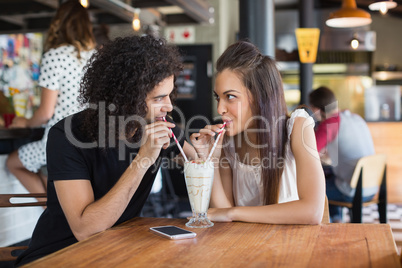 Young couple looking at each other while having drink together in restaurant