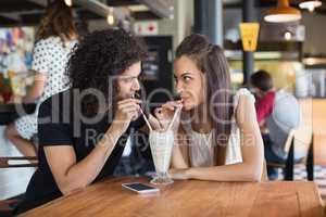 Young couple looking at each other while having drink together in restaurant
