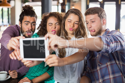 Playful friends taking selfie with digital tablet