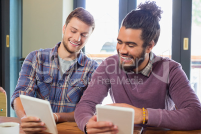 Male friends using tablet pc in restaurant