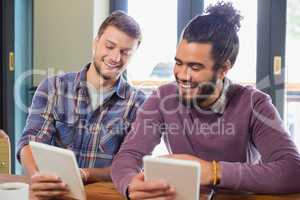 Male friends using tablet pc in restaurant
