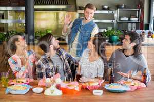 Friends greeting young man in restaurant