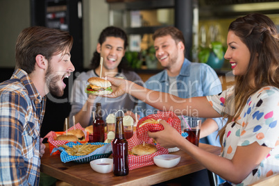 Smiling woman feeding burger to male friend