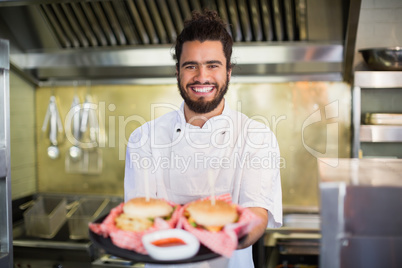 Chef holding burgers in plate at commercial kitchen