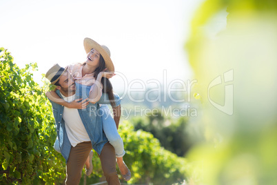 Happy couple piggybacking at vineyard