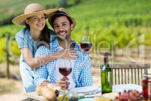 Portrait of young couple holding red wine at table