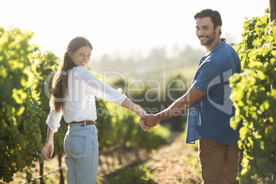 Portrait of smiling couple holding hands at vineyard