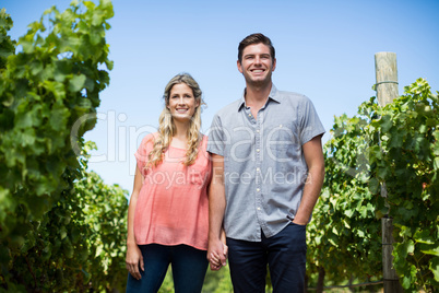 Happy couple holding hands at vineyard