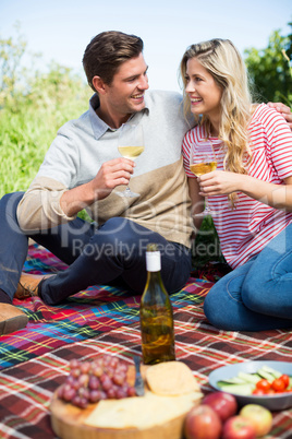 Happy young couple holding wineglasses on picnic blanket
