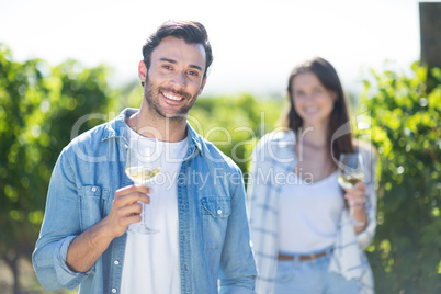 Happy young couple posing with wineglasses at vineyard