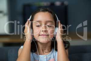 Girl listening to music on headphones in living room