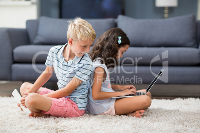 Boy looking behind while his sister using laptop in living room