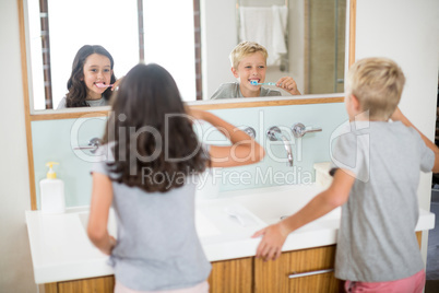 Siblings brushing their teeth in bathroom