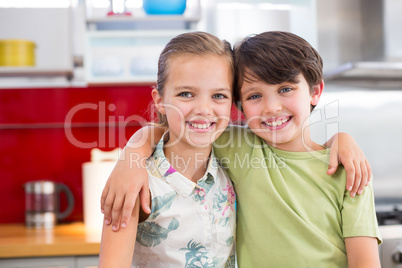 Siblings standing with arm around in kitchen