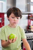 Boy holding apple in kitchen