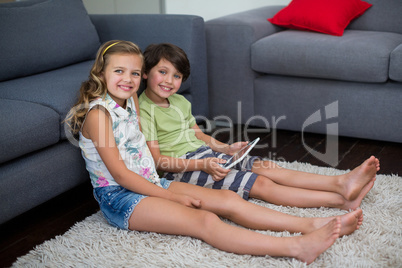 Portrait of siblings using digital tablet in living room