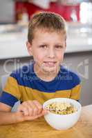 Portrait of smiling boy having breakfast cereal in kitchen