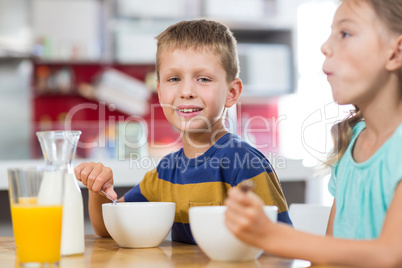 Smiling sibling having breakfast cereal in kitchen
