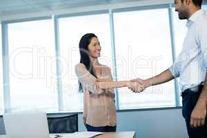 Smiling business people shaking hands during meeting at office