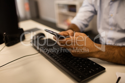 Cropped image of businessman using mobile phone while sitting at desk