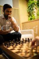 Young businessman playing chess with female colleague