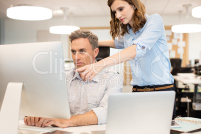 Female colleague assisting businessman working in office
