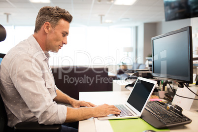 Side view of businessman using laptop in office