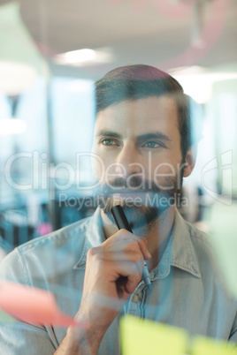 Thoughtful businessman looking at plans written on glass