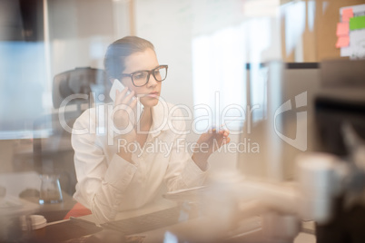 Businesswoman talking on mobile phone at office
